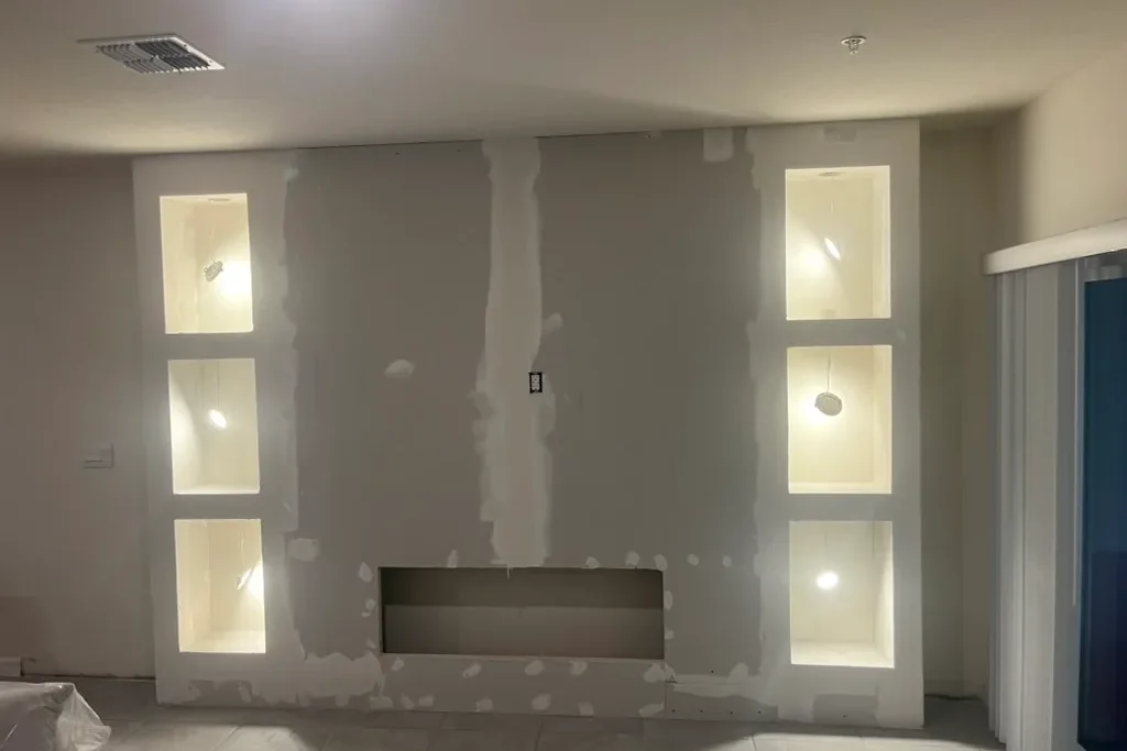 Custom media wall in progress with drywall, fireplace opening and illuminated niches