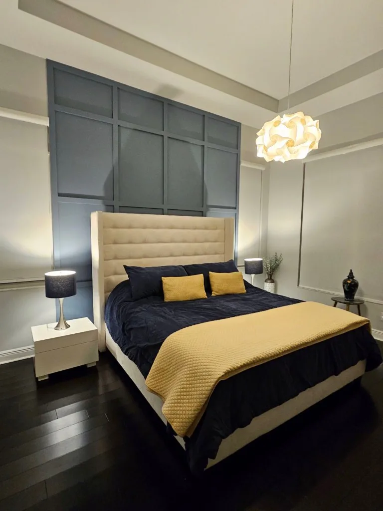 Finished bedroom with a dark paneled accent wall and coordinated trim